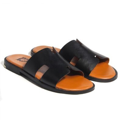 Black handcrafted leather slide sandal with wide strap, tan footbed, engraved back metal detail, and leather sole by Shoe Bespoke.